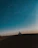A biker silhouetted against a starry Himalayan night sky, with rugged mountain peaks in the background.