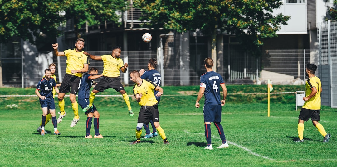 group of men playing soccer on green grass field during daytime