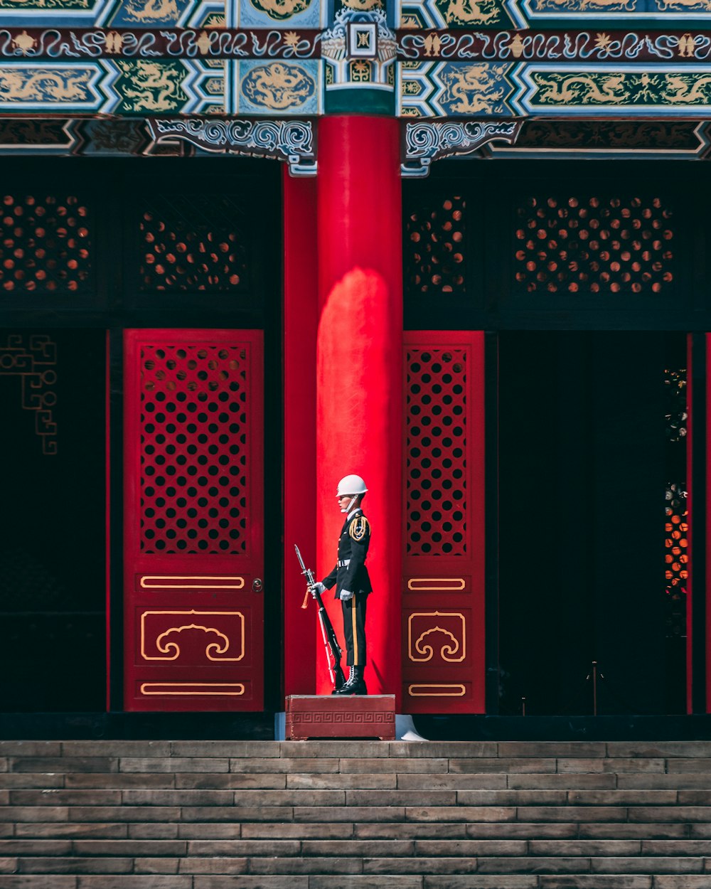 man in black jacket standing near red and black gate