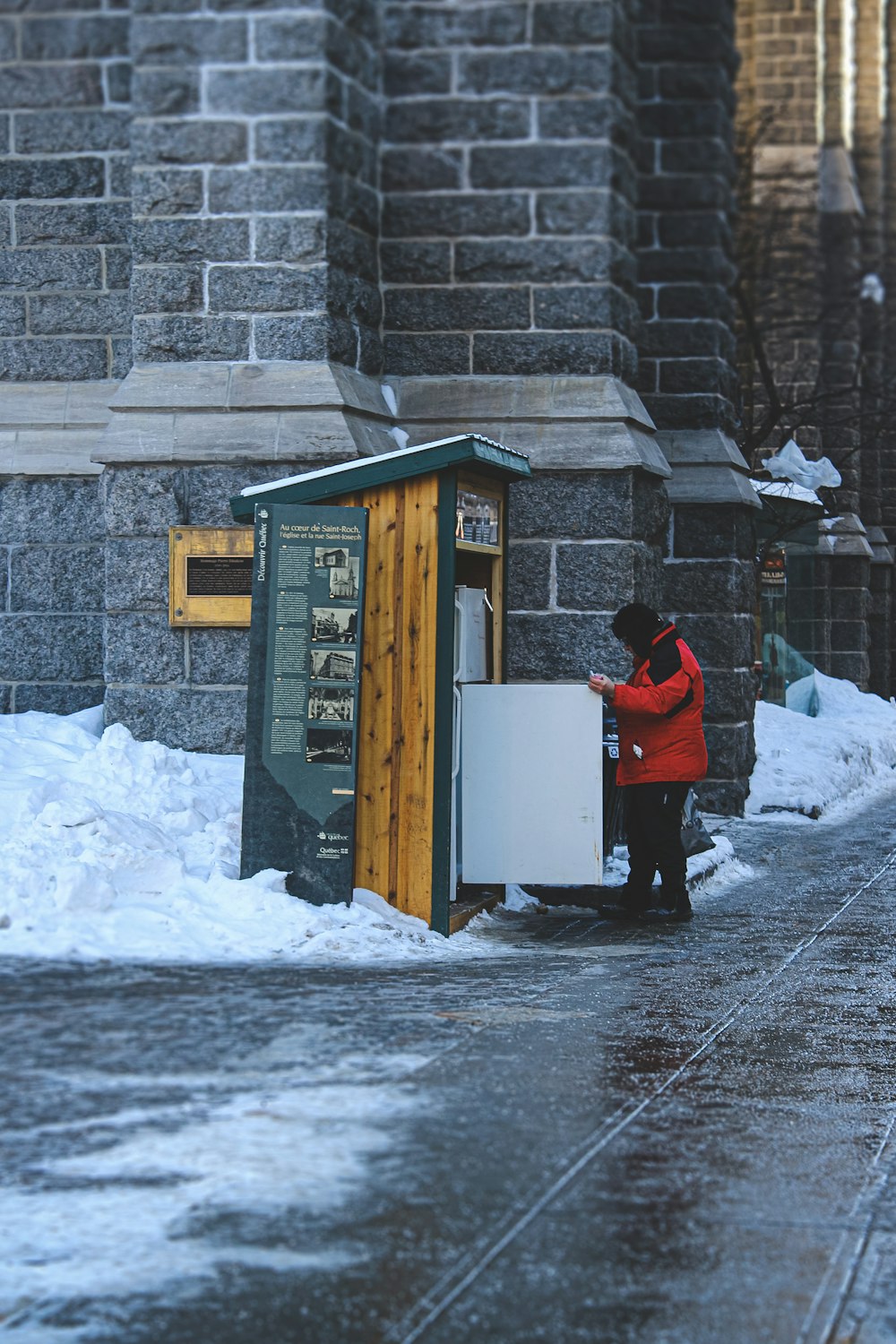 personne en veste rouge et pantalon noir debout sur un sol couvert de neige