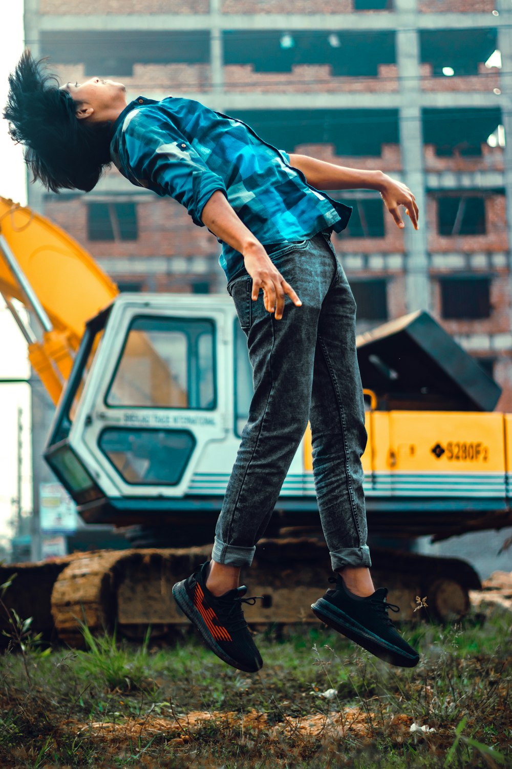 Hombre con camisa a cuadros azul y verde y jeans de mezclilla azules saltando sobre amarillo y negro