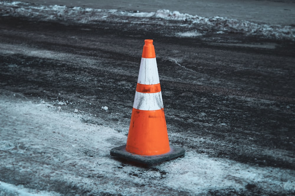 Cono de tráfico naranja y blanco sobre arena negra