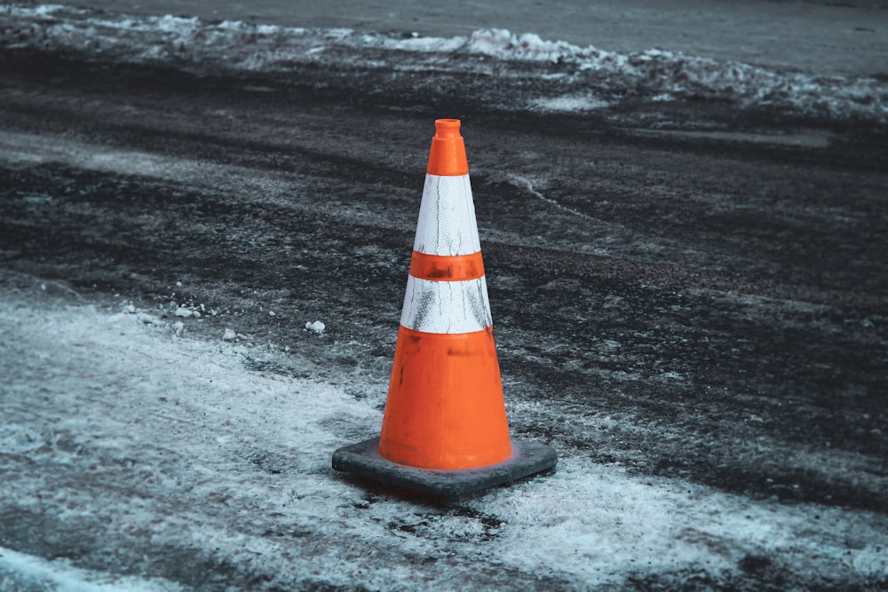 cone de tráfego laranja e branco na areia preta