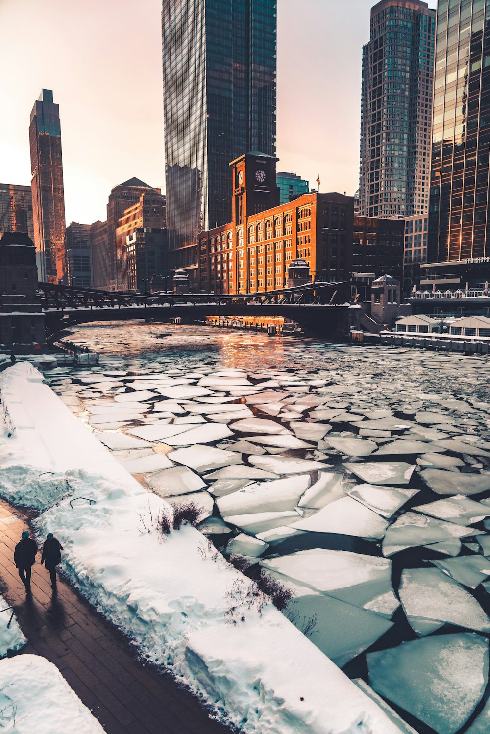 people walking on snow covered ground near body of water during daytime