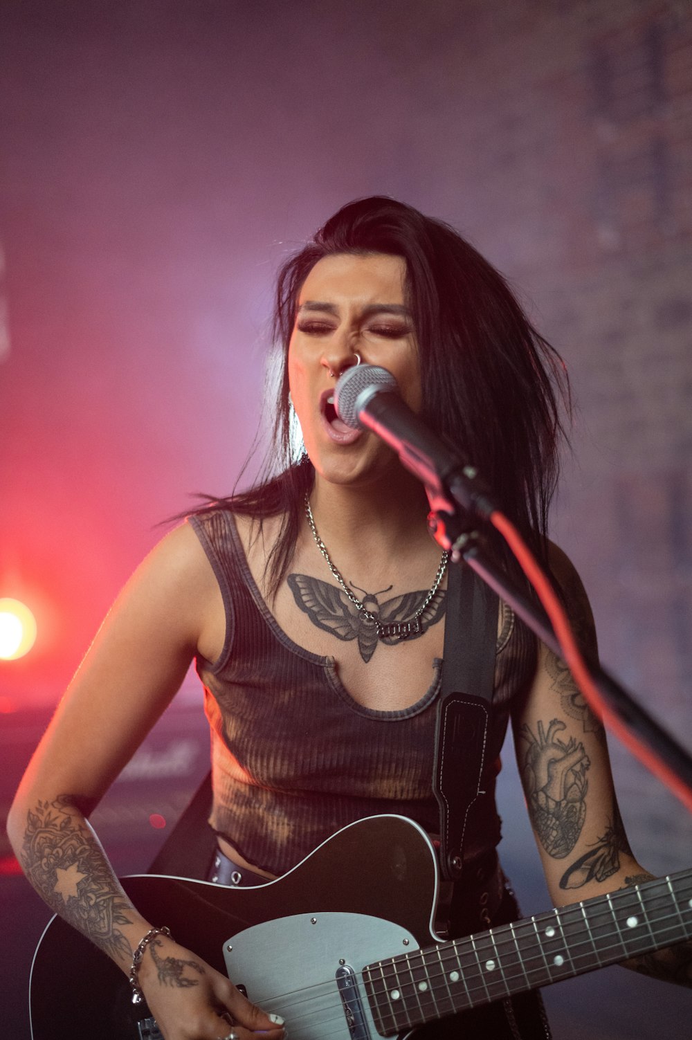 mujer con camiseta negra sin mangas cantando