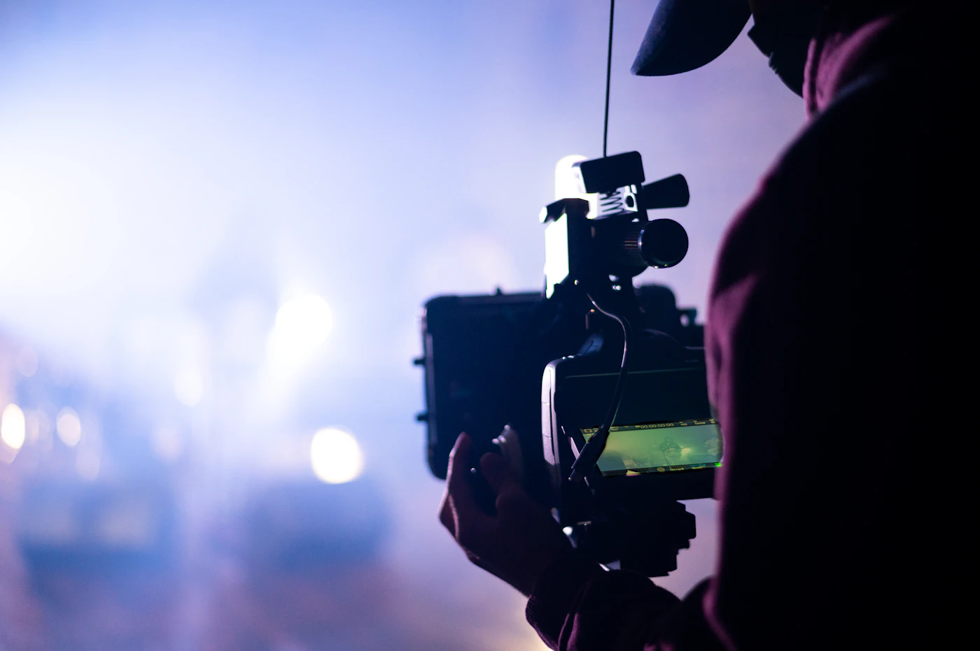 Operator holding a cinema camera rig in soft stage light