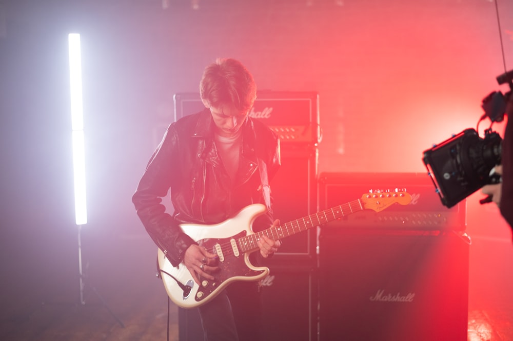 man in black jacket playing electric guitar