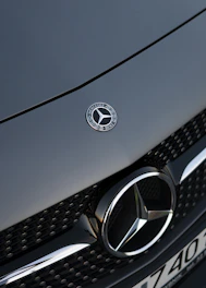 Close-up of a Mercedes-Benz emblem on a shiny car grille.