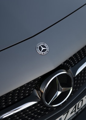 silver mercedes benz emblem on gray car