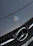 Close-up of a sleek Mercedes-Benz grille gleaming under soft showroom lighting.