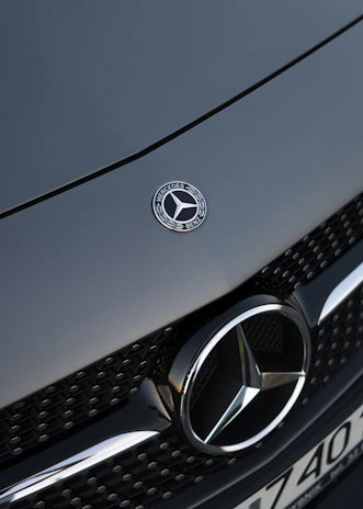 Close-up of the golden emblem on a black Mercedes grille shining under soft lighting.