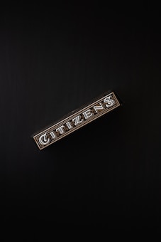 A rectangular box with the word 'CITIZENS' written in bold, decorative letters on its side, set against a dark background. The design is intricate, featuring patterns and metallic accents.