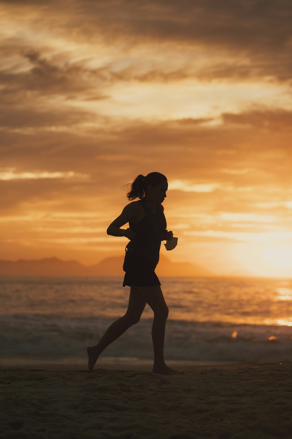 夕暮れ時の浜辺に立つ女性のシルエット