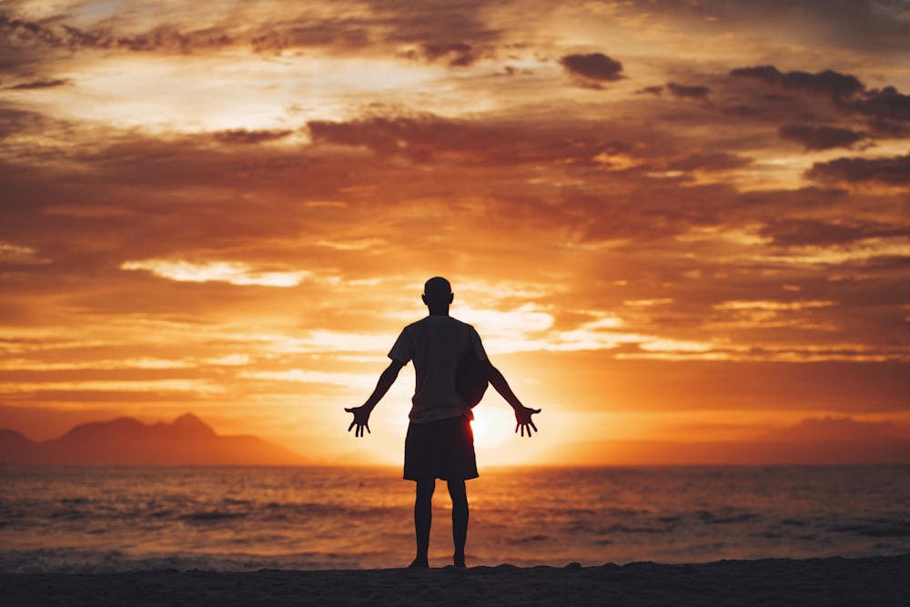 Silueta del hombre que corre en la playa durante la puesta del sol