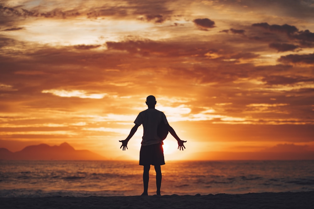 silhouette of man running on beach during sunset