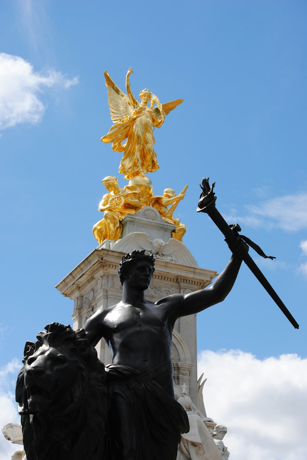 man holding sword statue under blue sky during daytime