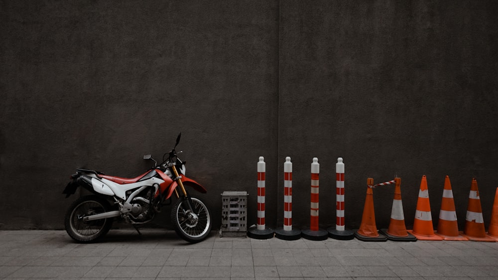 red and white motorcycle parked beside gray wall