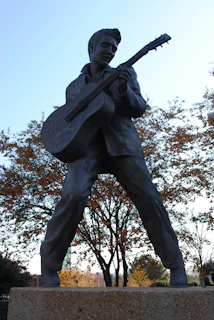 man holding stick statue under white sky during daytime