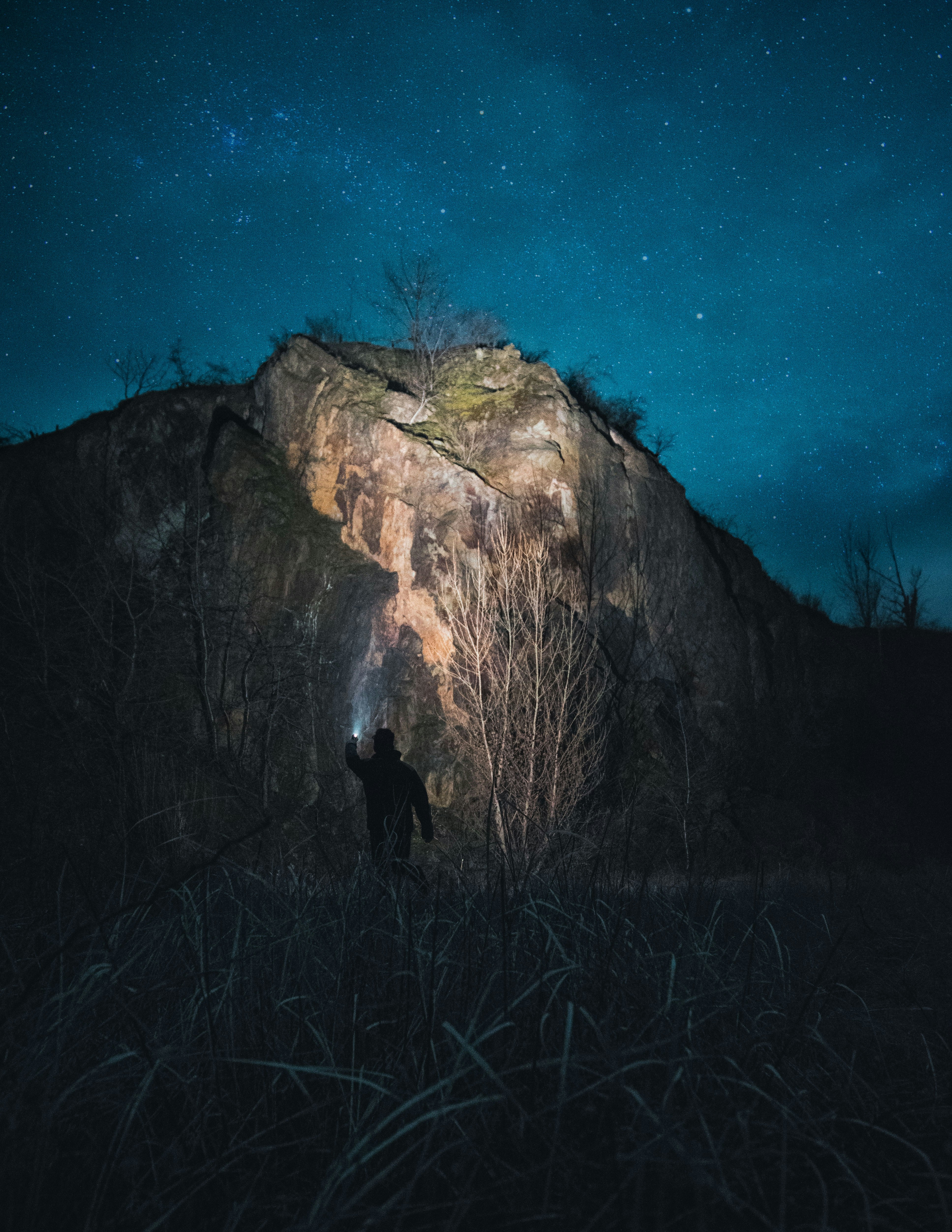 personne debout sur l’herbe brune près de la montagne brune pendant la nuit