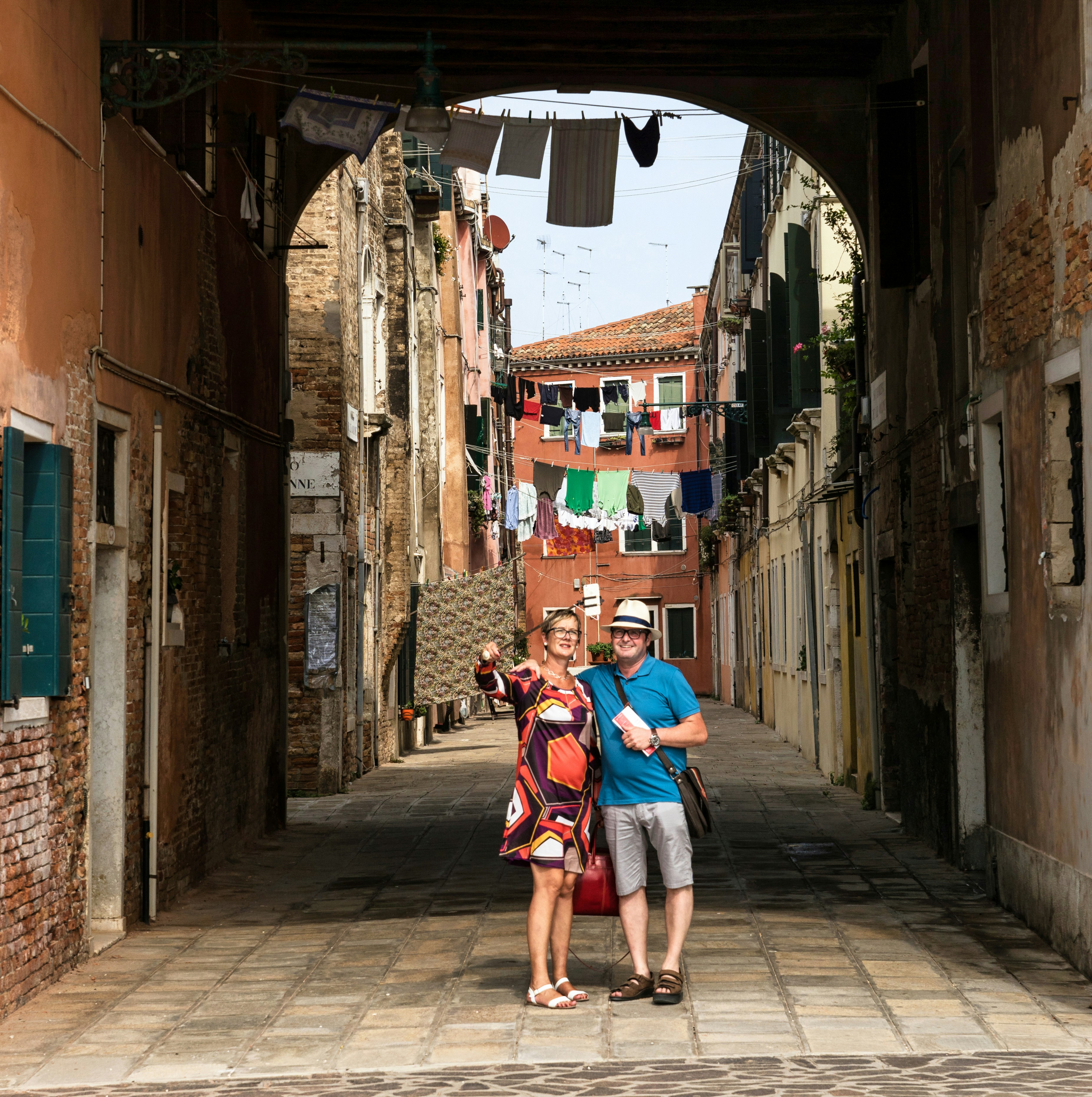 man in red and blue shirt walking on street during daytime