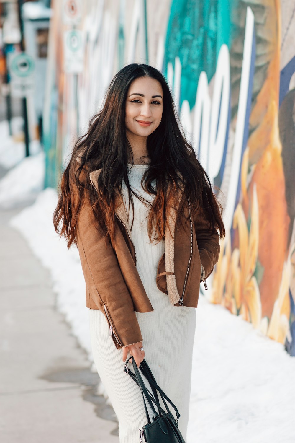 woman in brown coat standing on snow covered ground during daytime