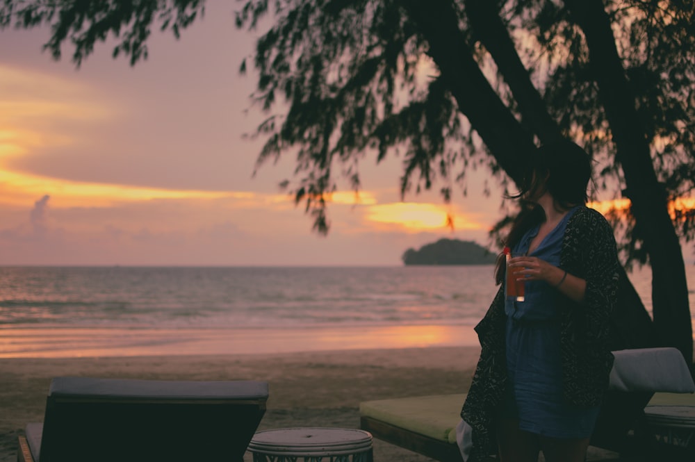 woman in blue dress standing on beach during sunset