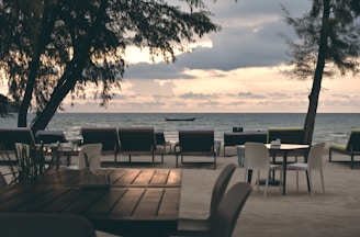 brown wooden table and chairs near sea during daytime