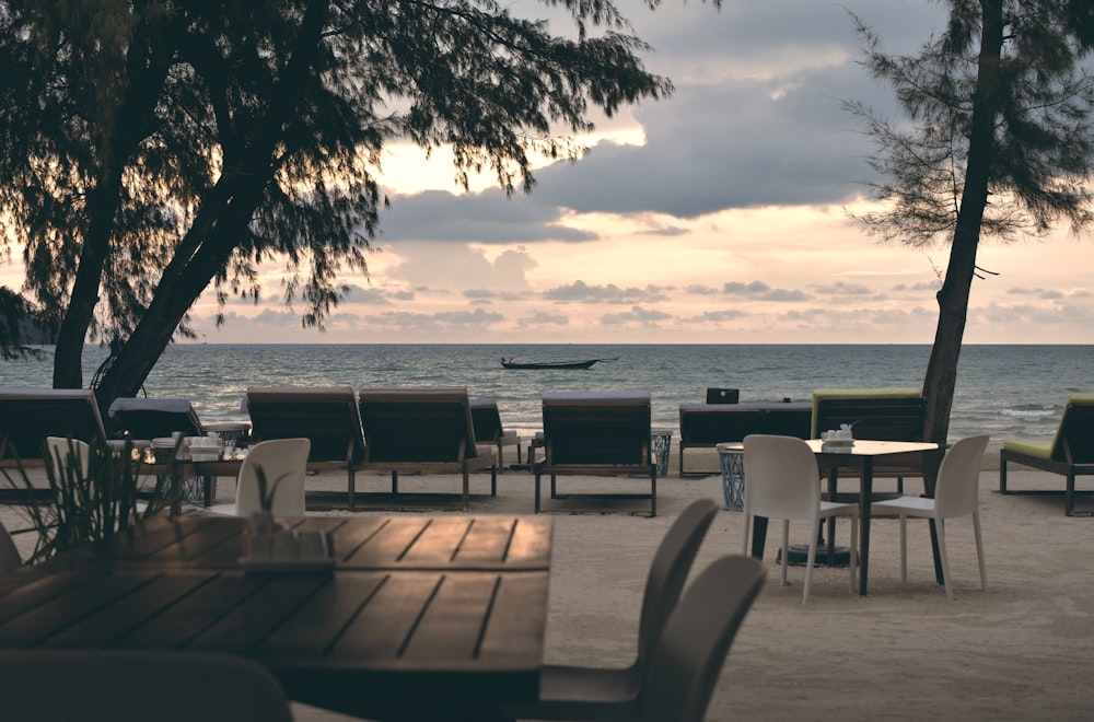 brown wooden table and chairs near sea during daytime