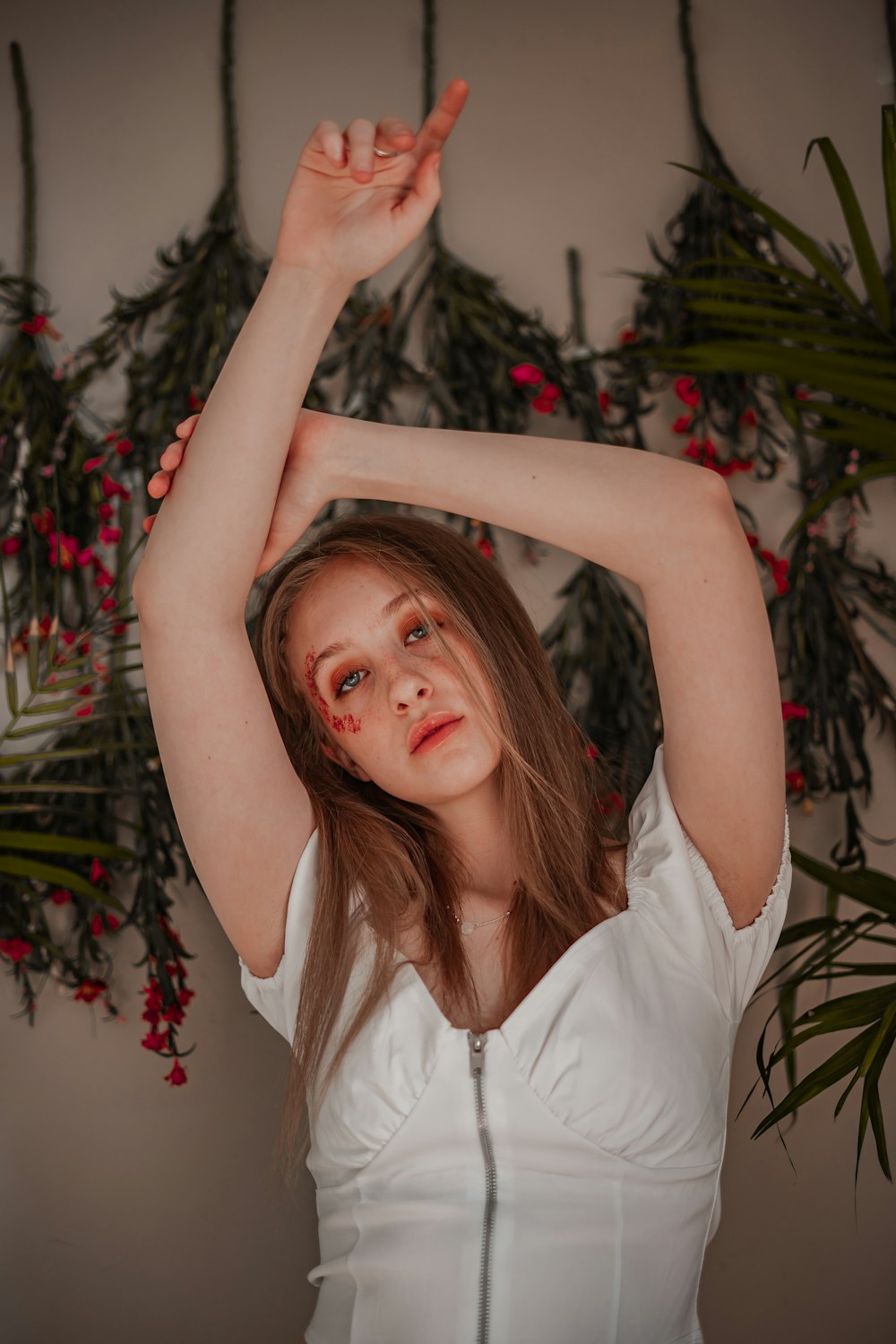 menina na camisa branca sem mangas que está perto da planta verde