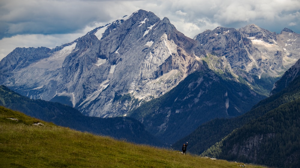 people walking on green grass field near mountain during daytime