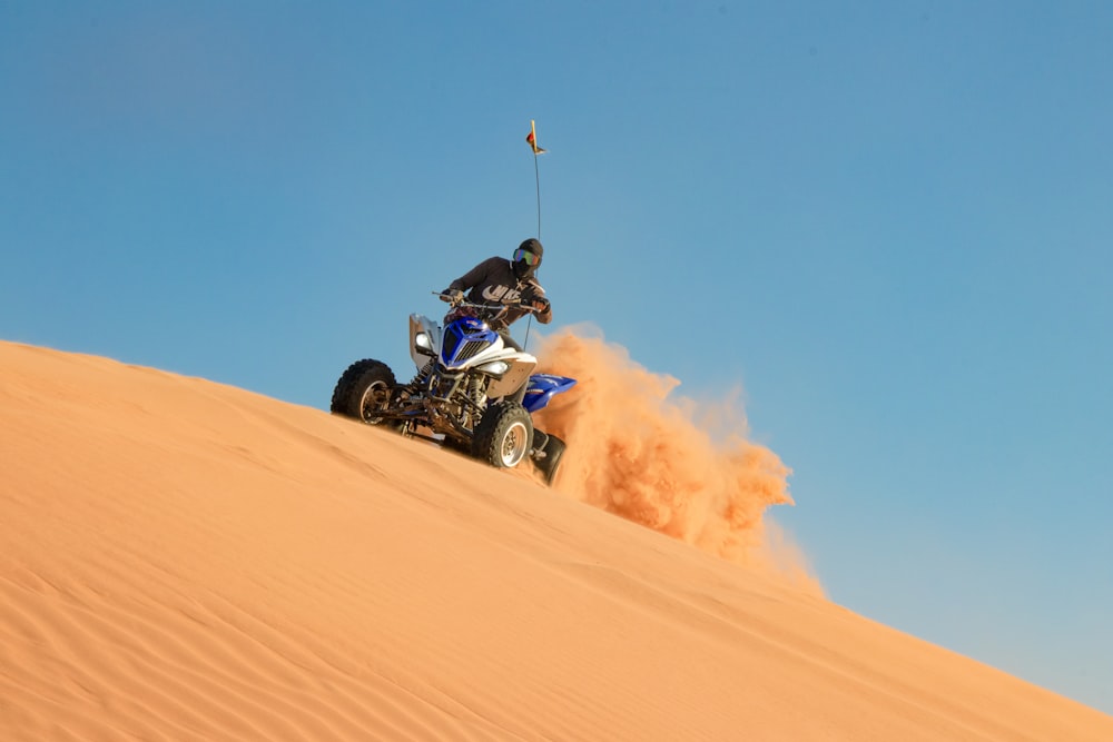 昼間の砂漠で青と黒のスポーツバイクに乗る男