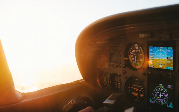 A sleek cockpit view at sunrise, with instruments softly glowing and the Retezat mountains visible through the windshield.