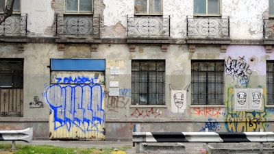 Exterior of a boarded-up townhouse with graffiti on the walls.