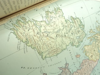 A detailed vintage map of Ireland is depicted, showing various towns, geographical features, and bodies of water. The map includes labelled regions and is oriented at an angle, giving a dynamic presentation of the island's topography.