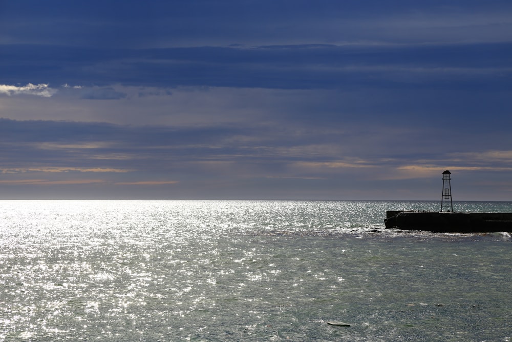 ocean waves crashing on black rock under blue sky during daytime