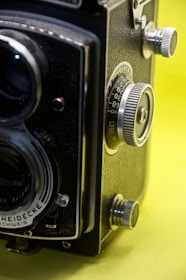 Close-up of a vintage film camera against a yellow backdrop, highlighting intricate details of the lens.