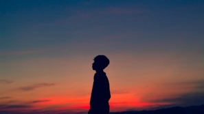 A sunset silhouette of a small business owner reflecting on their journey outside their shop.