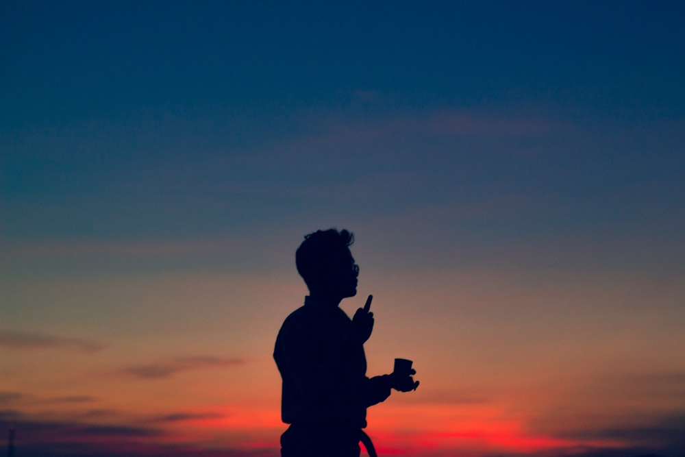 Silhouette eines Mannes, der die Kamera während des Sonnenuntergangs hält
