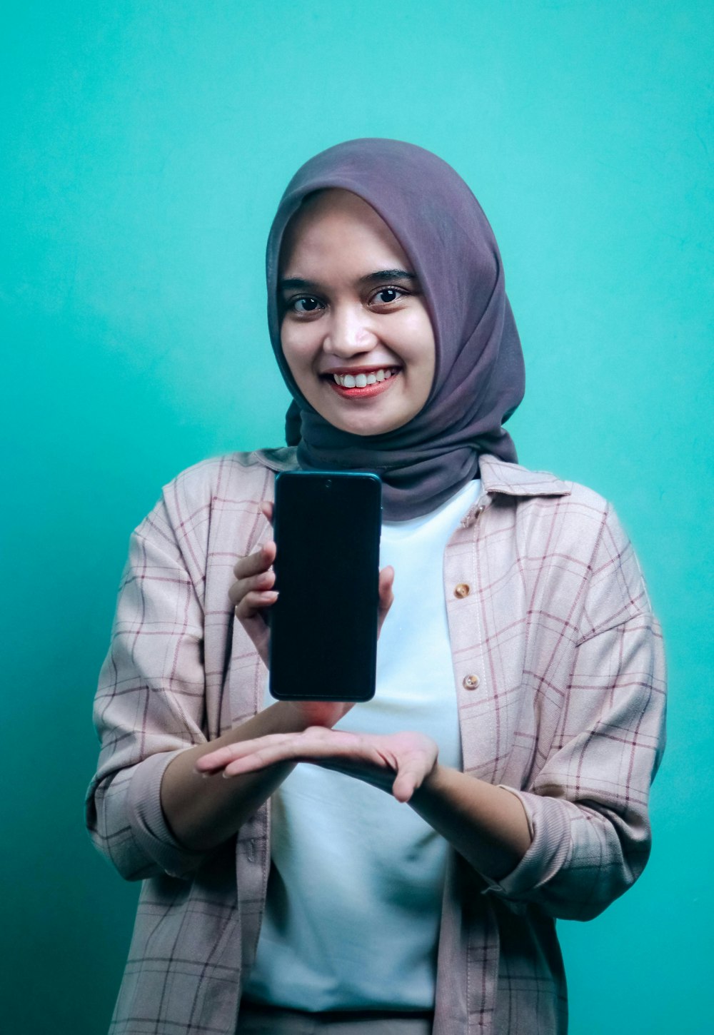 woman in gray hijab holding black smartphone