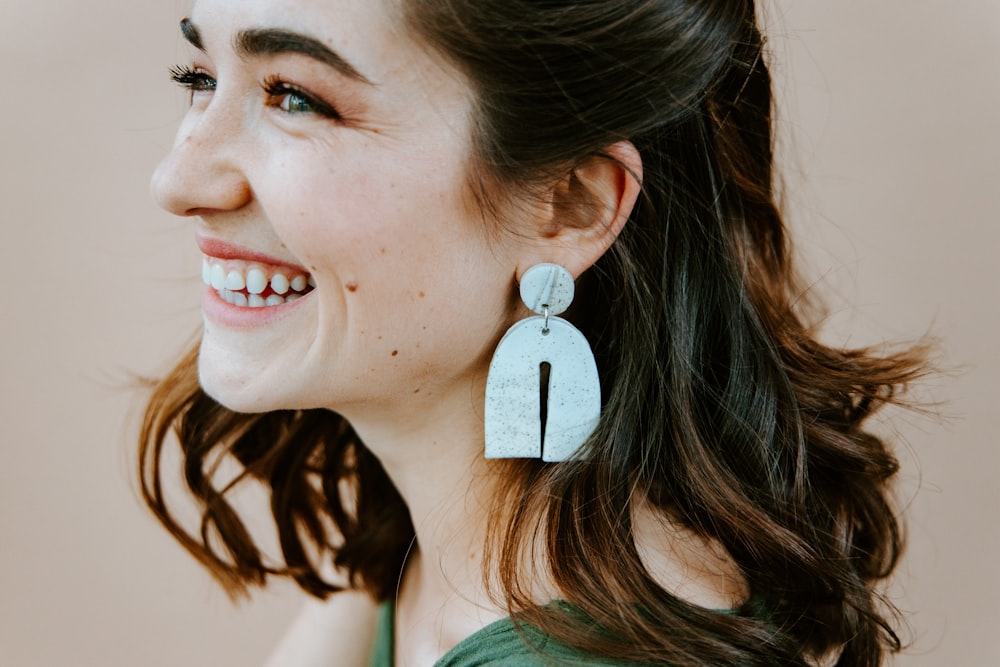 woman in green shirt with silver heart pendant earrings