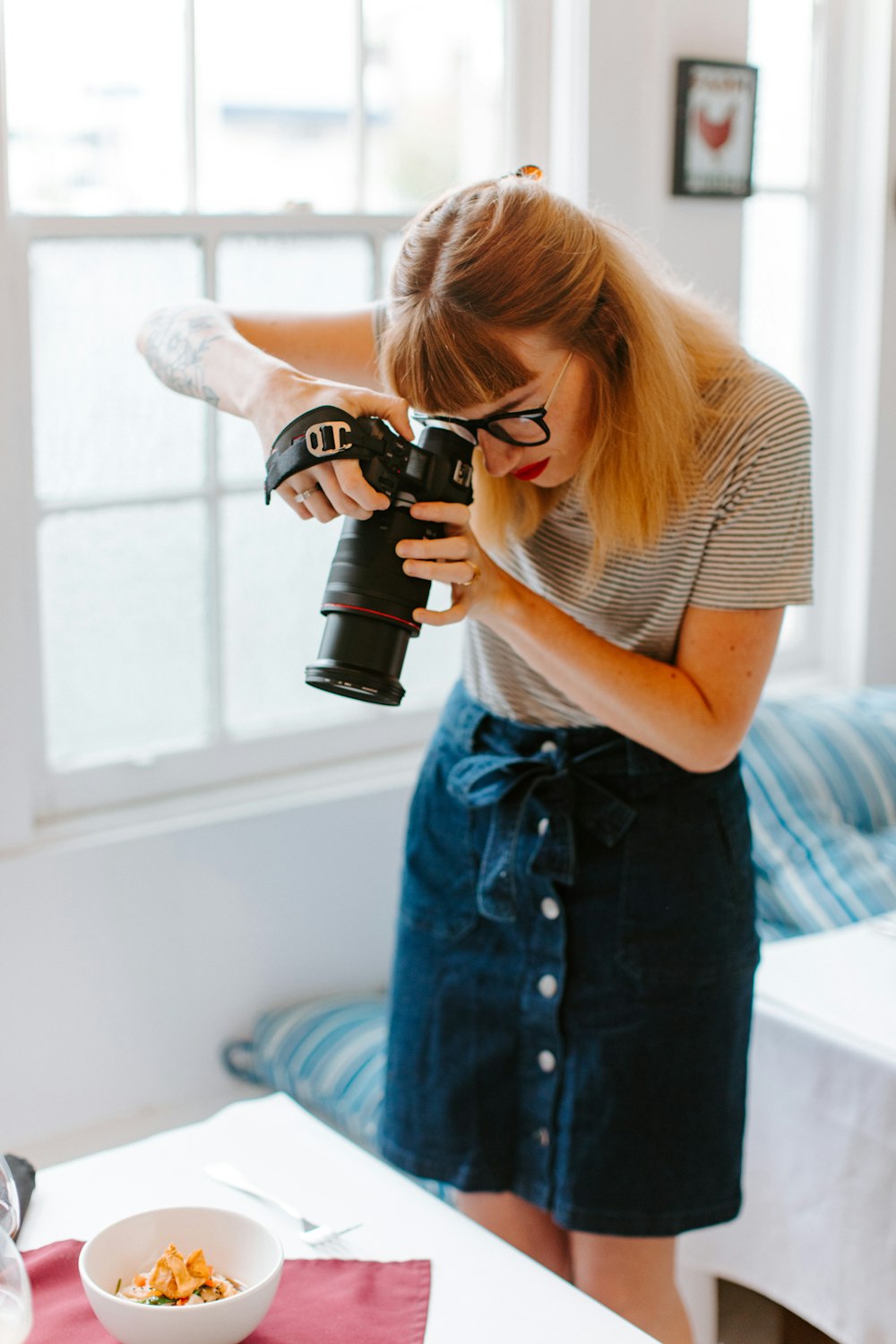 woman in white and black stripe shirt and blue denim shorts holding black dslr camera