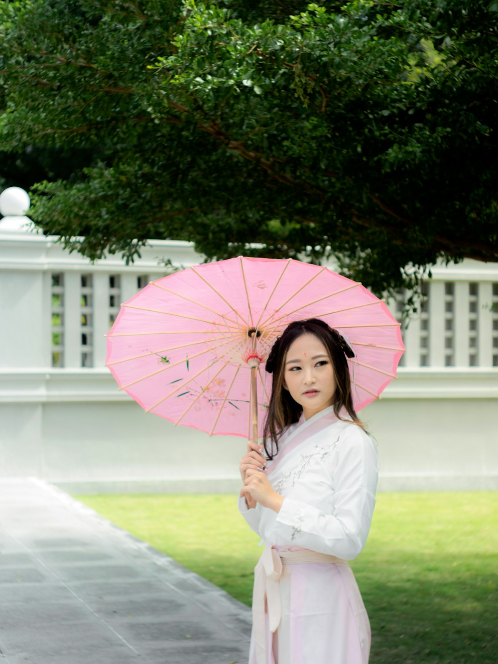 a woman in a white dress holding a pink umbrella