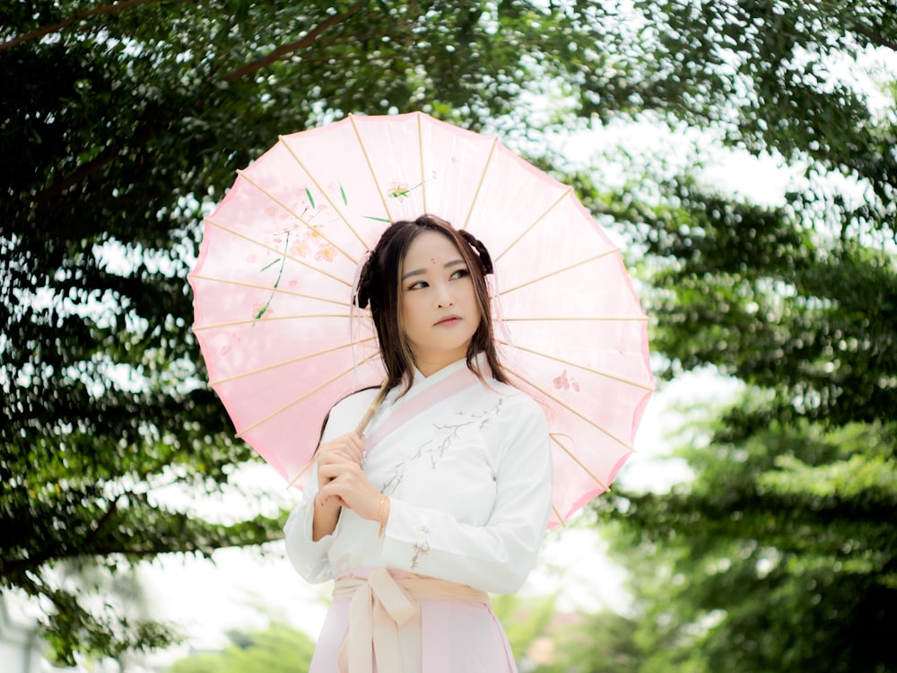 a woman in a kimono holding a pink umbrella