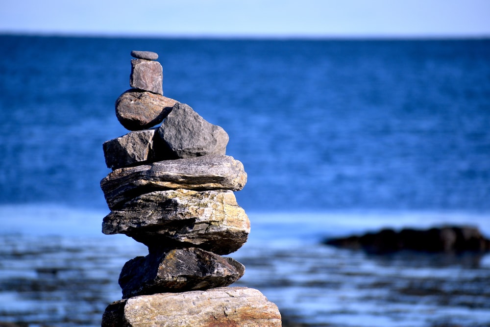 stack of gray and brown rocks near body of water during daytime