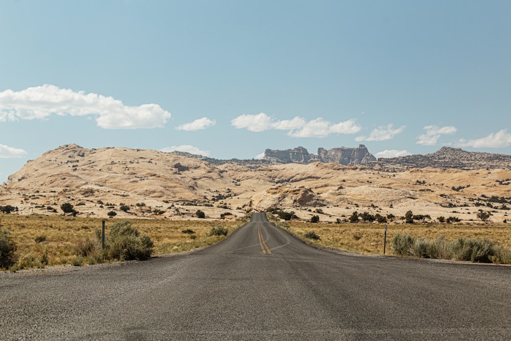 gray asphalt road in the middle of brown field during daytime