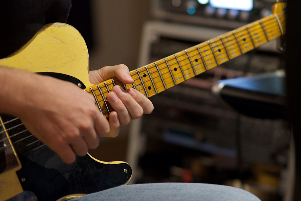 person playing yellow and black acoustic guitar