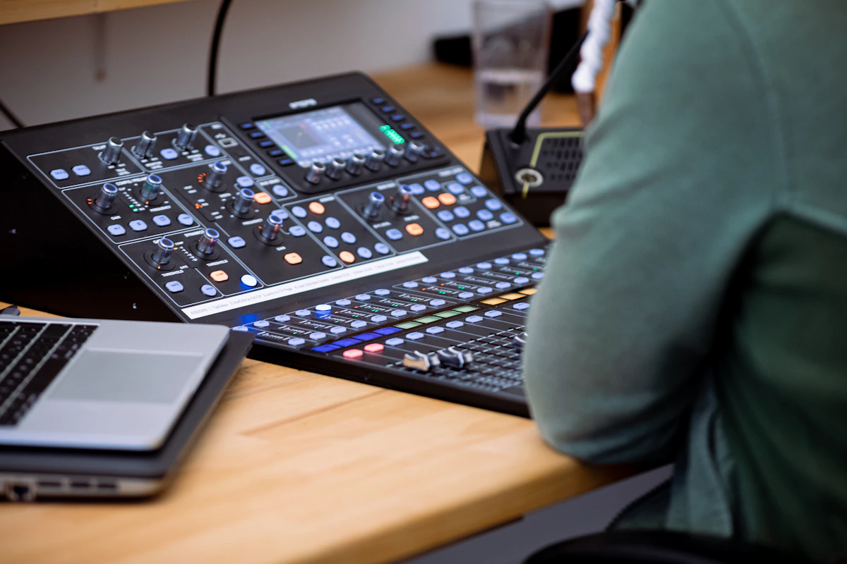 Mixing console faders in a professional music studio with blue lighting