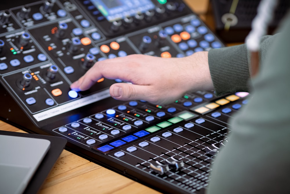 person playing audio mixer on brown wooden table