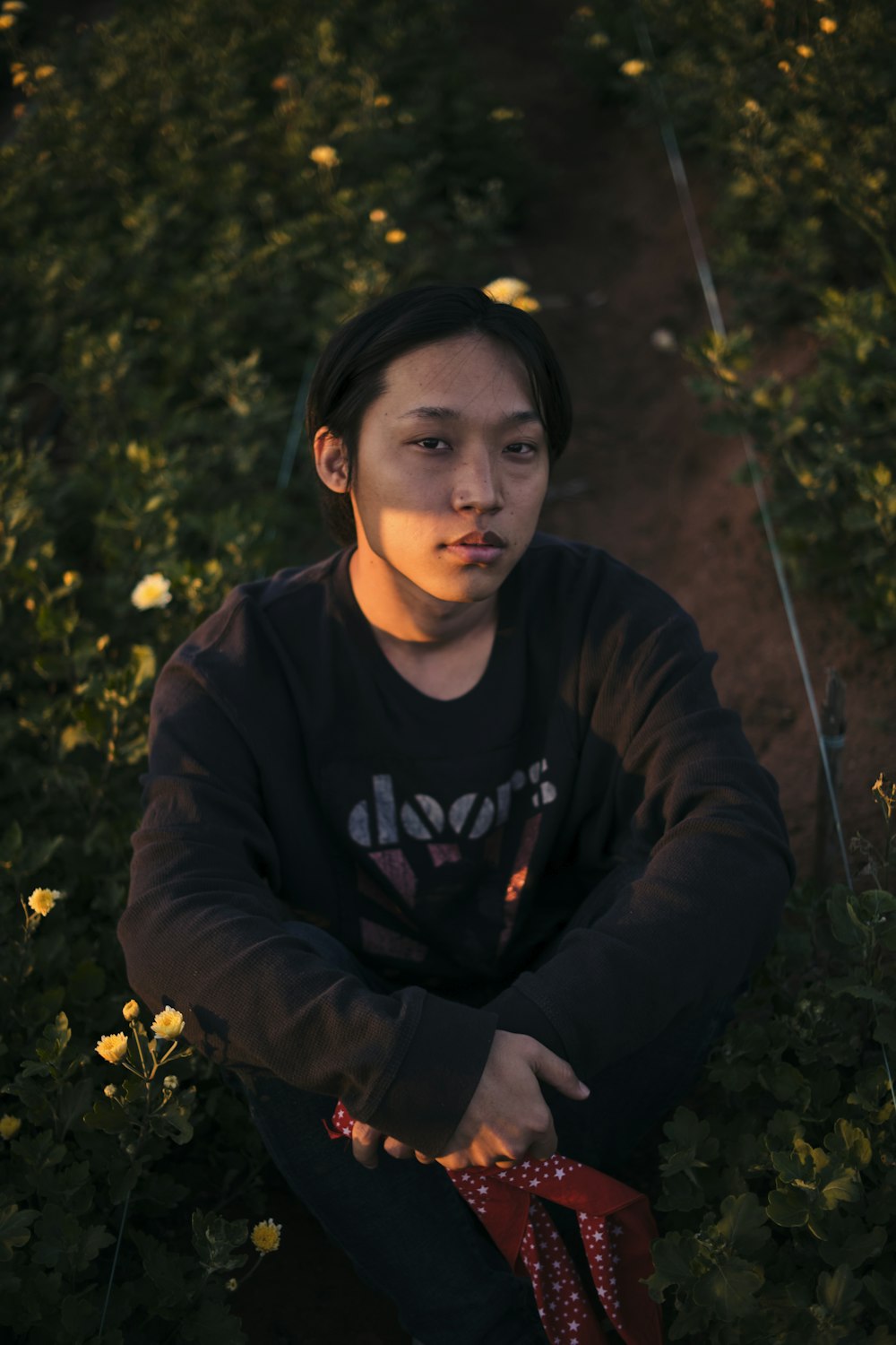 man in black and yellow hoodie sitting on green grass field