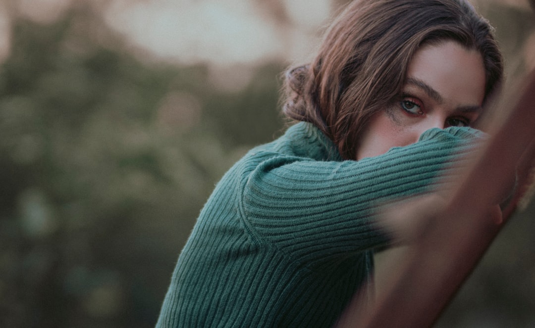 woman in green sweater holding her hair
